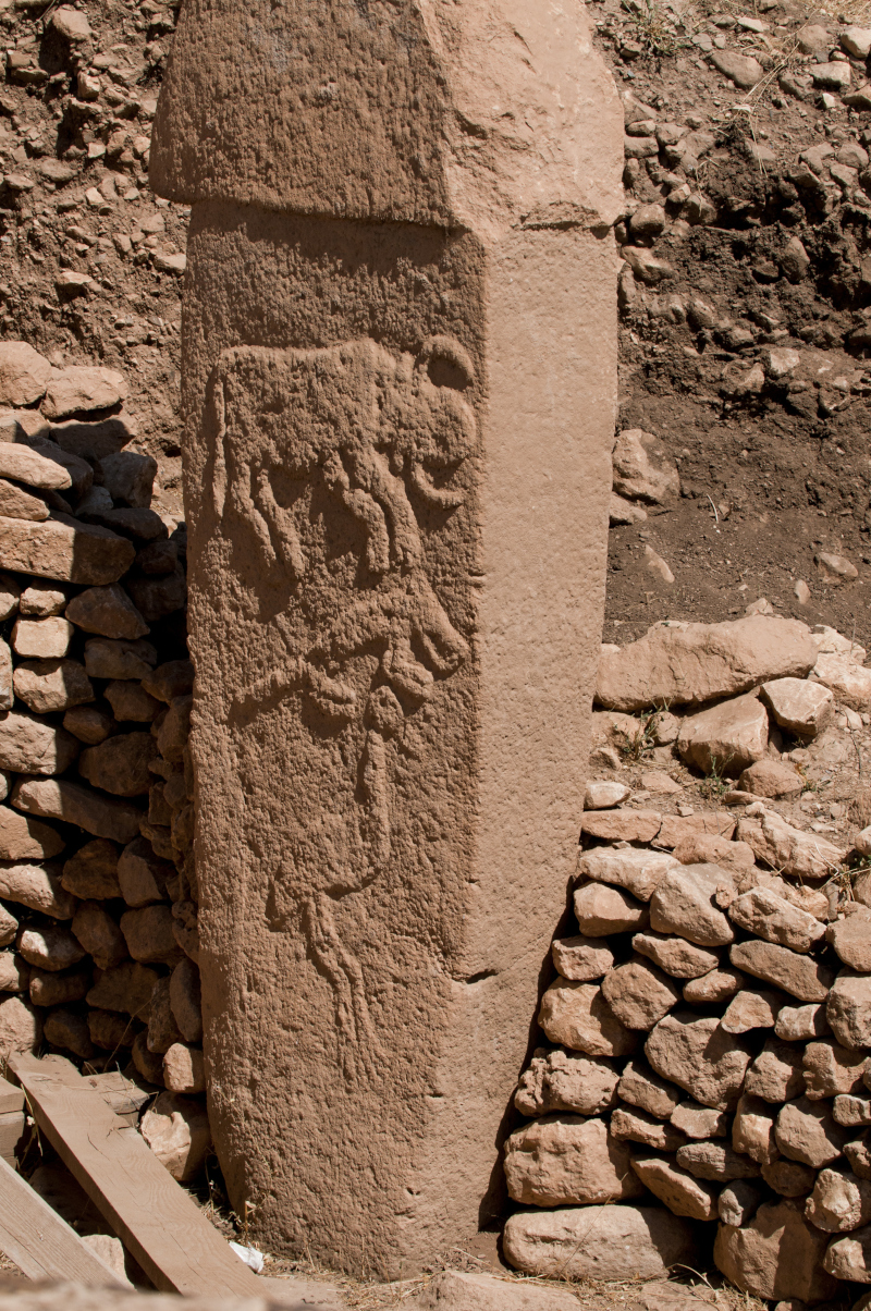 Low relief carvings of an aurochs, a fox and a crane on a limestone pillar